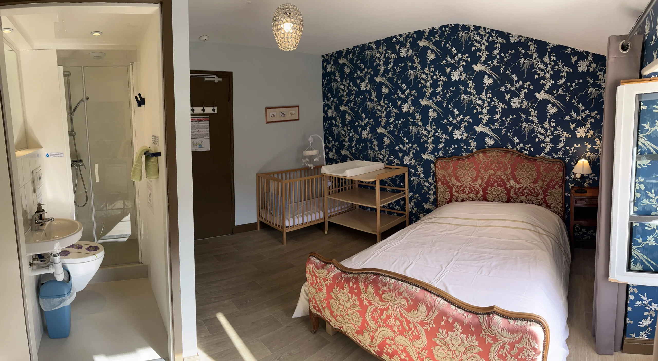 Jolie chambre avec un lit double et un lit de bébé, une table à langer, une salle d'eau avec WC.